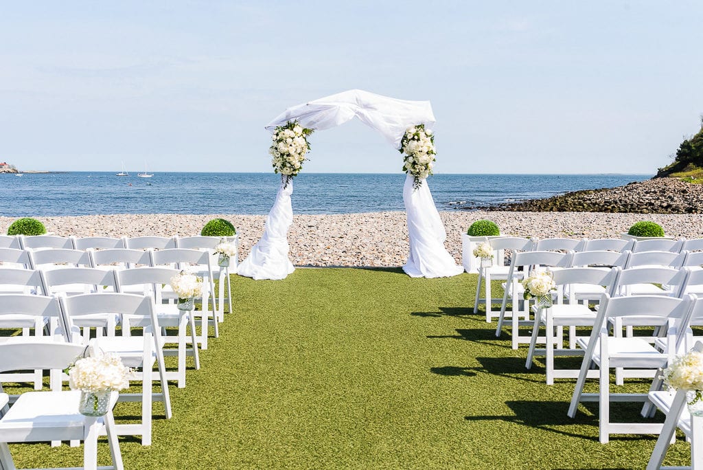 Ceremony on the beach with white florals at the oceanview of Nahant