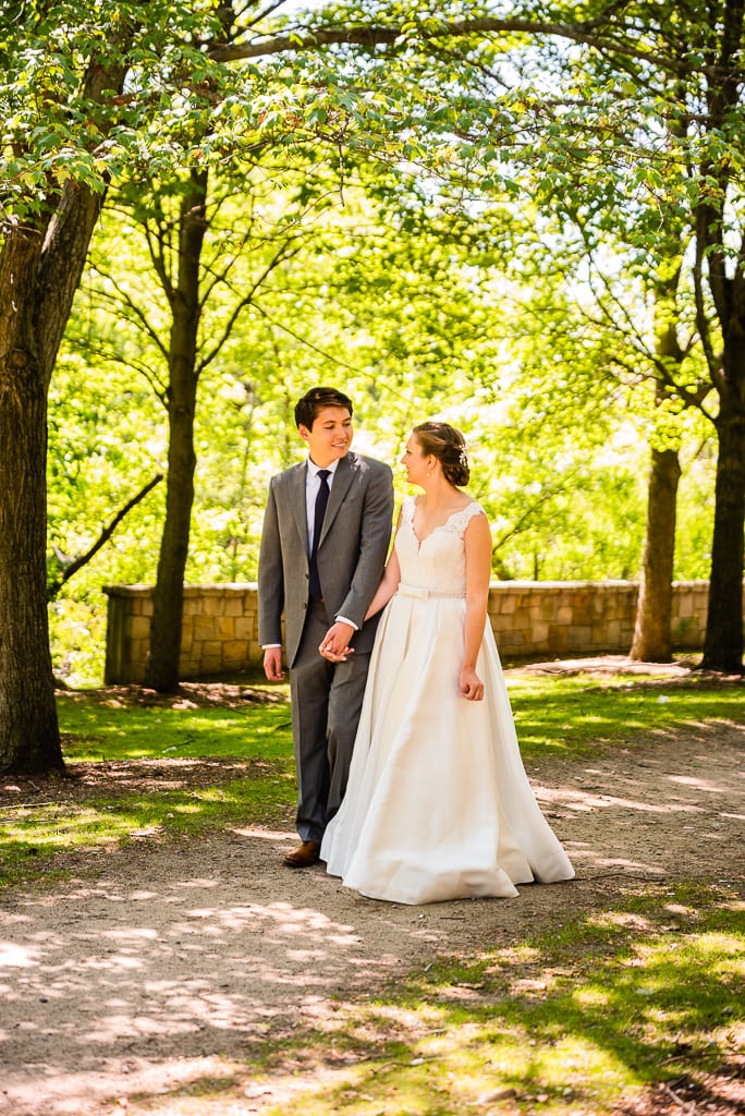 Bride and groom walking along a sunlight path in landry park
