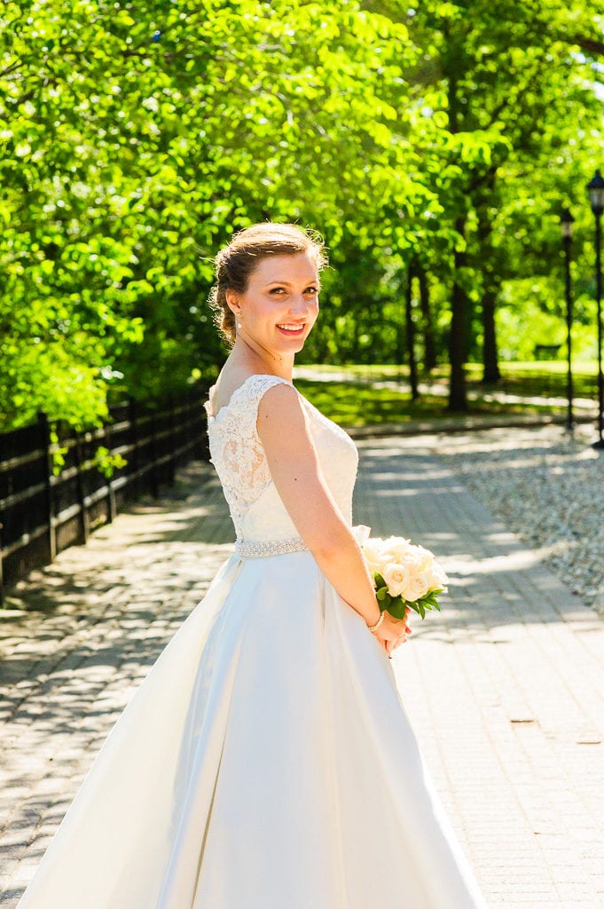 Bride standing in sunlight on a path
