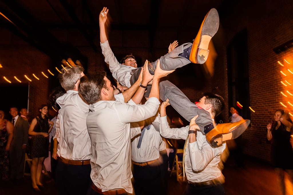 Groom being tossed into the air during wedding reception
