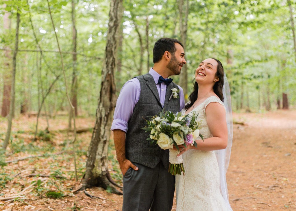 Bride and groom laughing on trail in woods